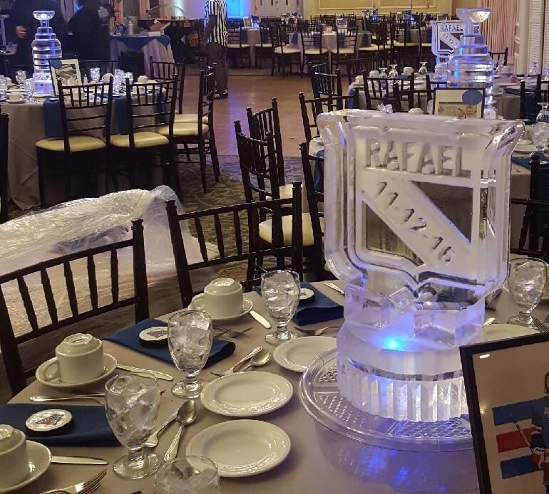 Elegant banquet table with glassware and blue lighting, featuring a white “RAFAEL” sign centerpiece