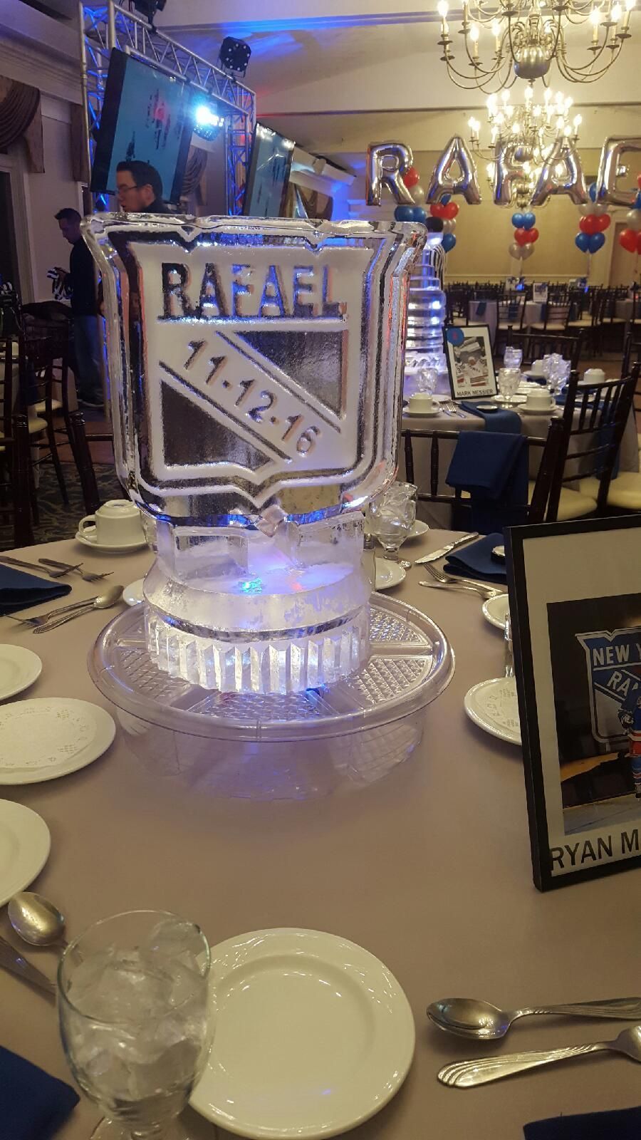 Ice sculpture of a beer can labeled “RAFAEL” on a banquet table in a decorated event hall