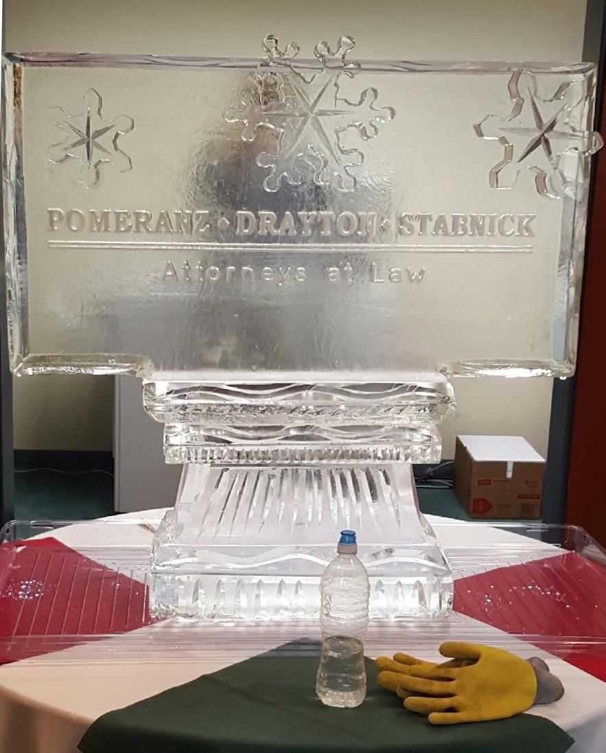 Clear ice sculpture display with etched snowflakes, a small water bottle, and a yellow glove on a table
