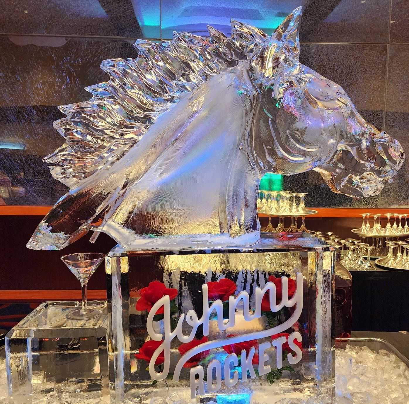 Crystal horse sculpture with “Johnny Rockets” sign on a reflective display, lit by blue and warm lights