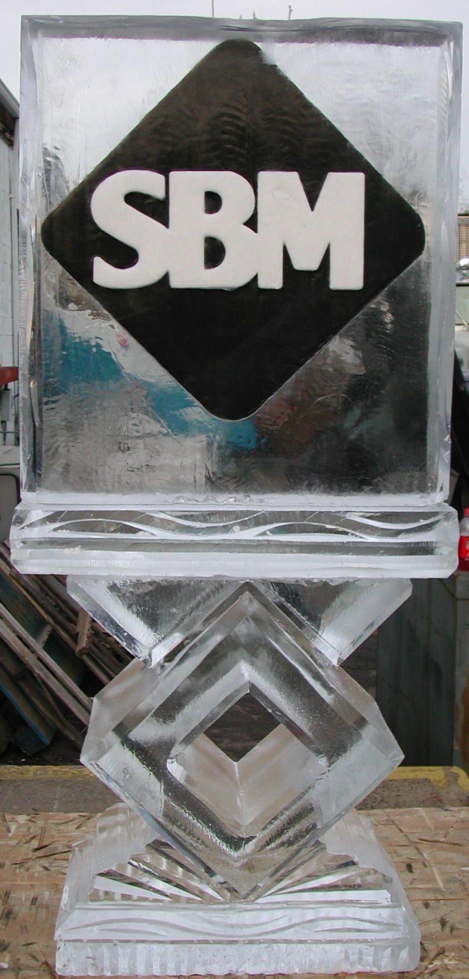 Stacked clear glass awards with a black diamond “SBM” logo plaque on top.