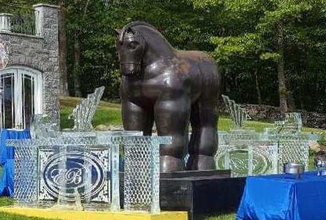 Dark gorilla statue behind a blue-and-white gate in a garden setting