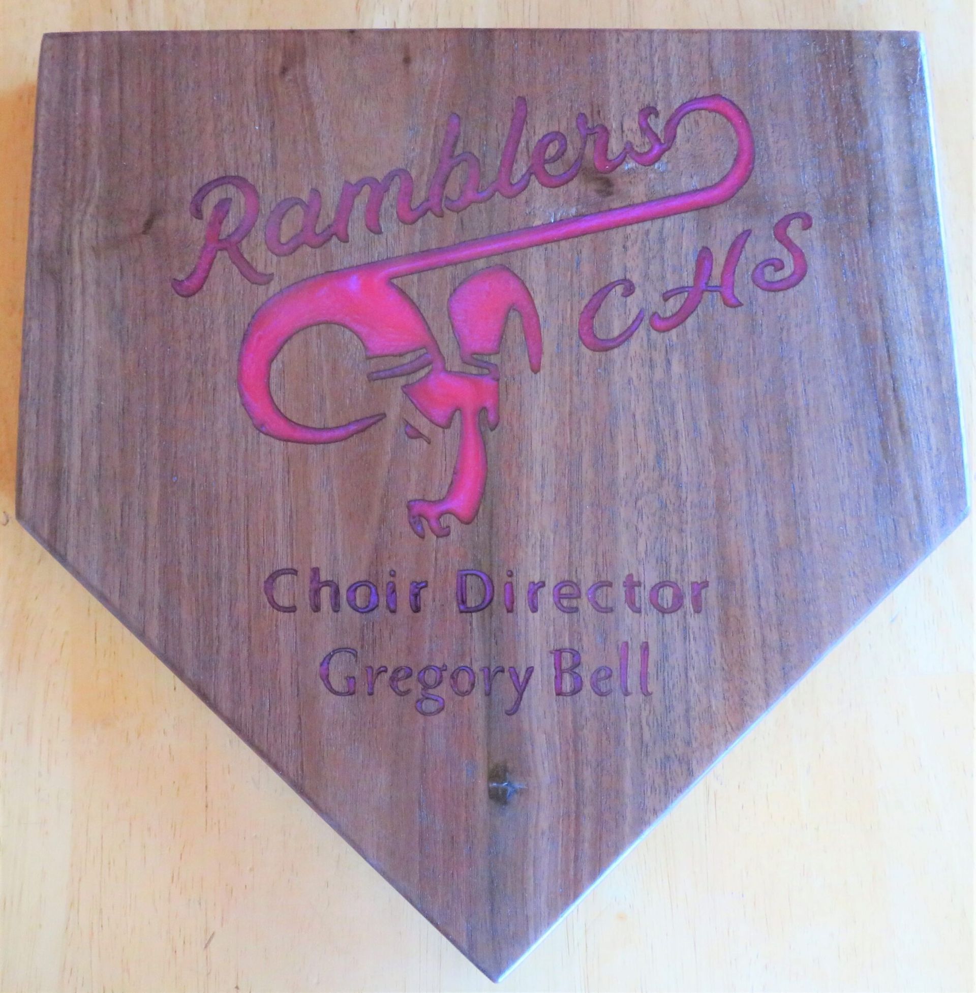 Wooden plaque reading “Ramblers Chorus” and “Choir Director Gregory Bell” in pink lettering