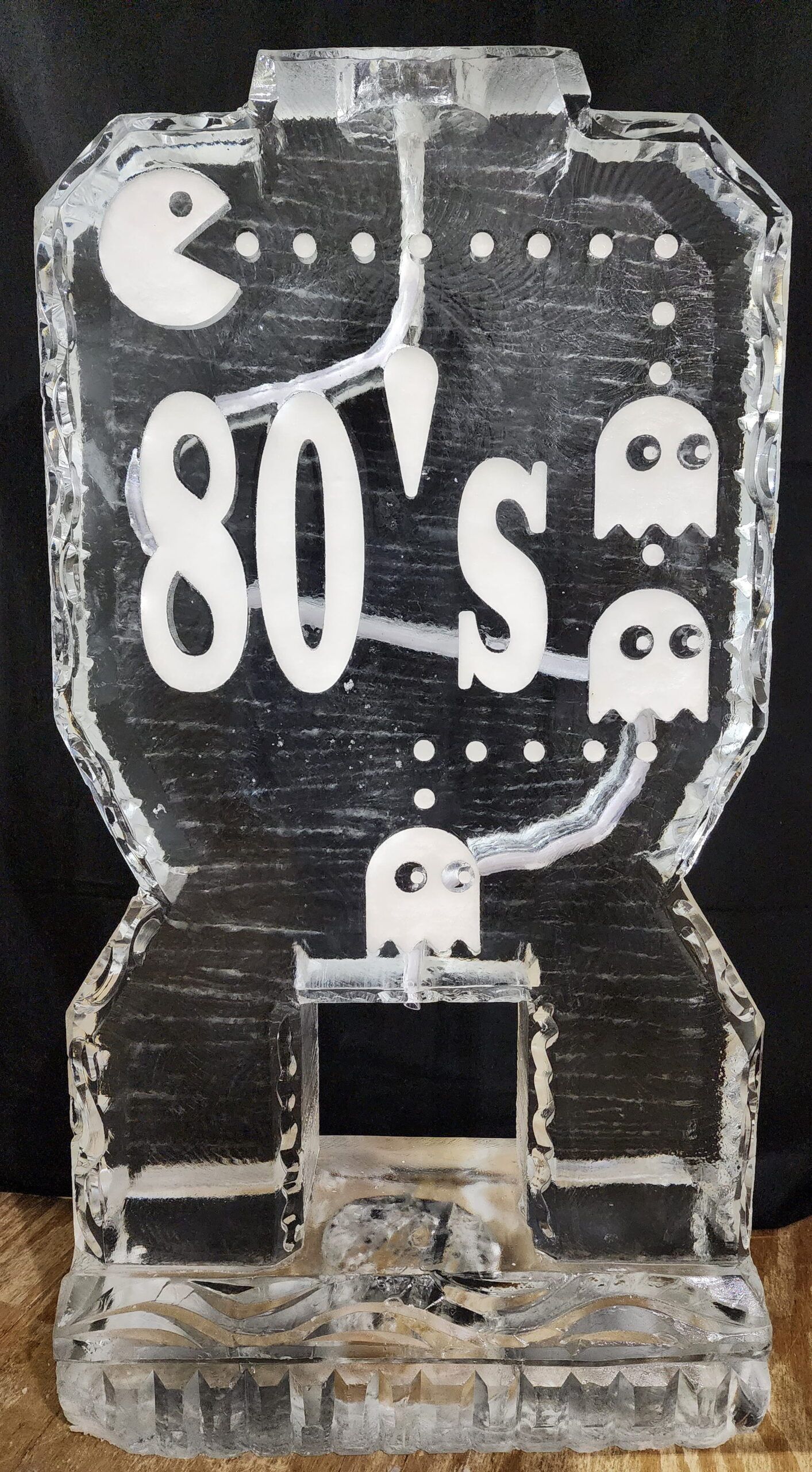 80’s-themed Pac-Man style arcade sign with ghost icons on a clear stand