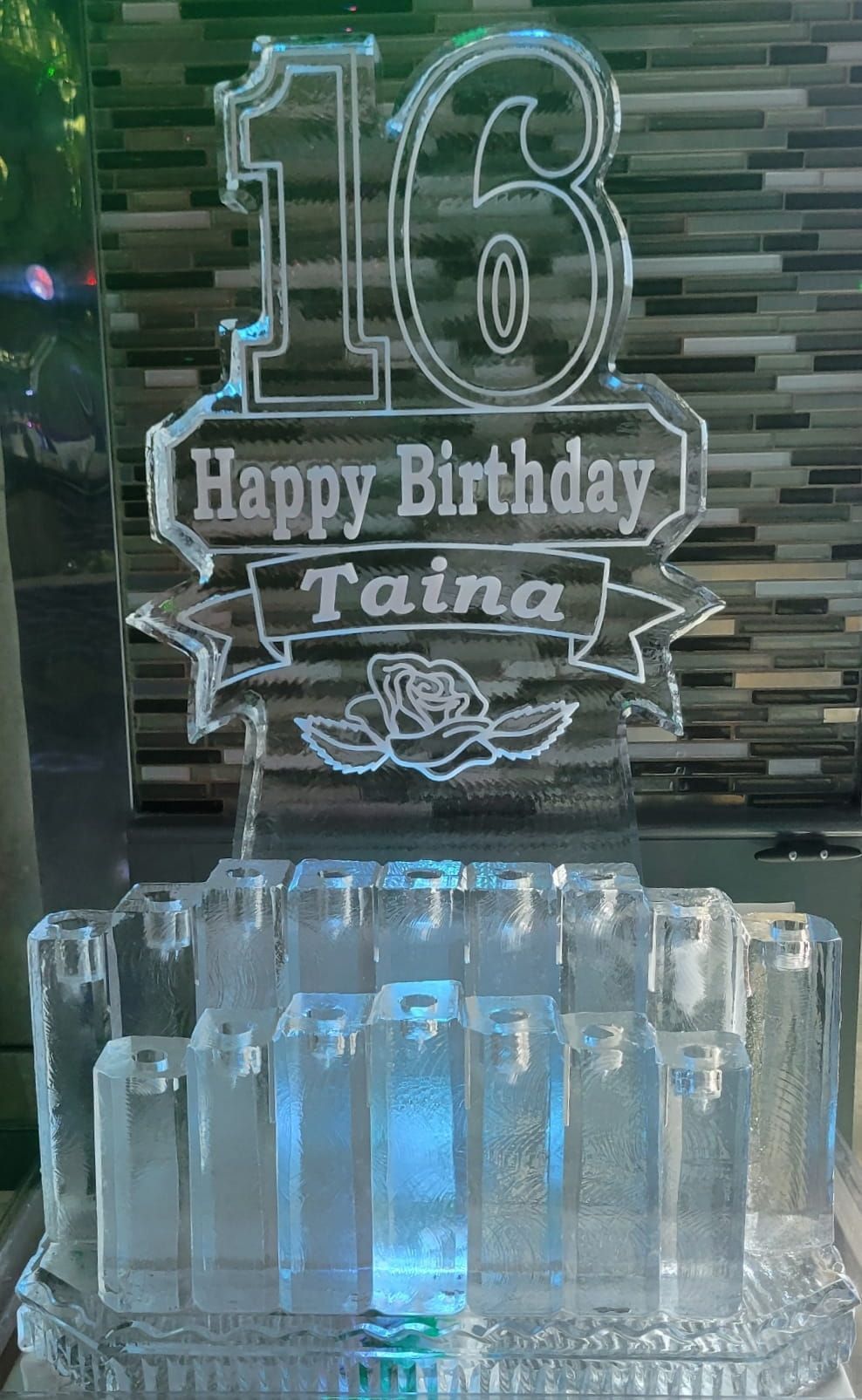 16th birthday cake topper with “Happy Birthday Taine” above a blue-lit ice sculpture cake display