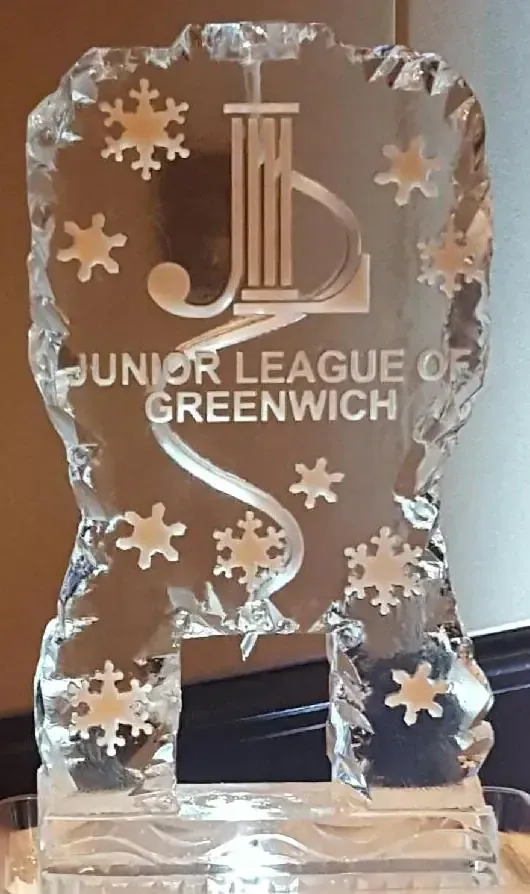 Clear glass trophy with snowflake cutouts and “Junior League of Greenwich” engraved on it.