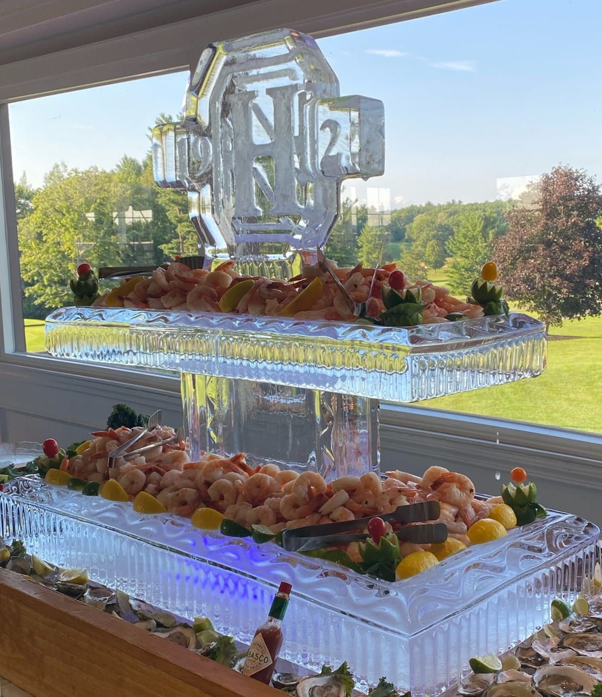 Three-tier fruit display with a silver monogram topper by a window, in a bright room