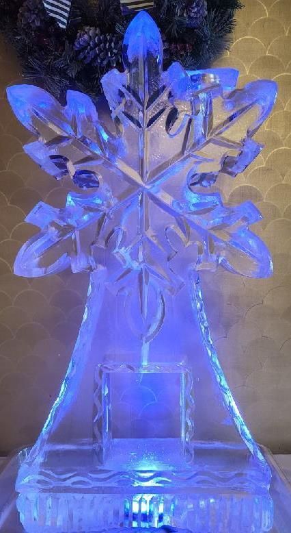 Blue-lit crystal snowflake ornament on a clear stand against a beige background