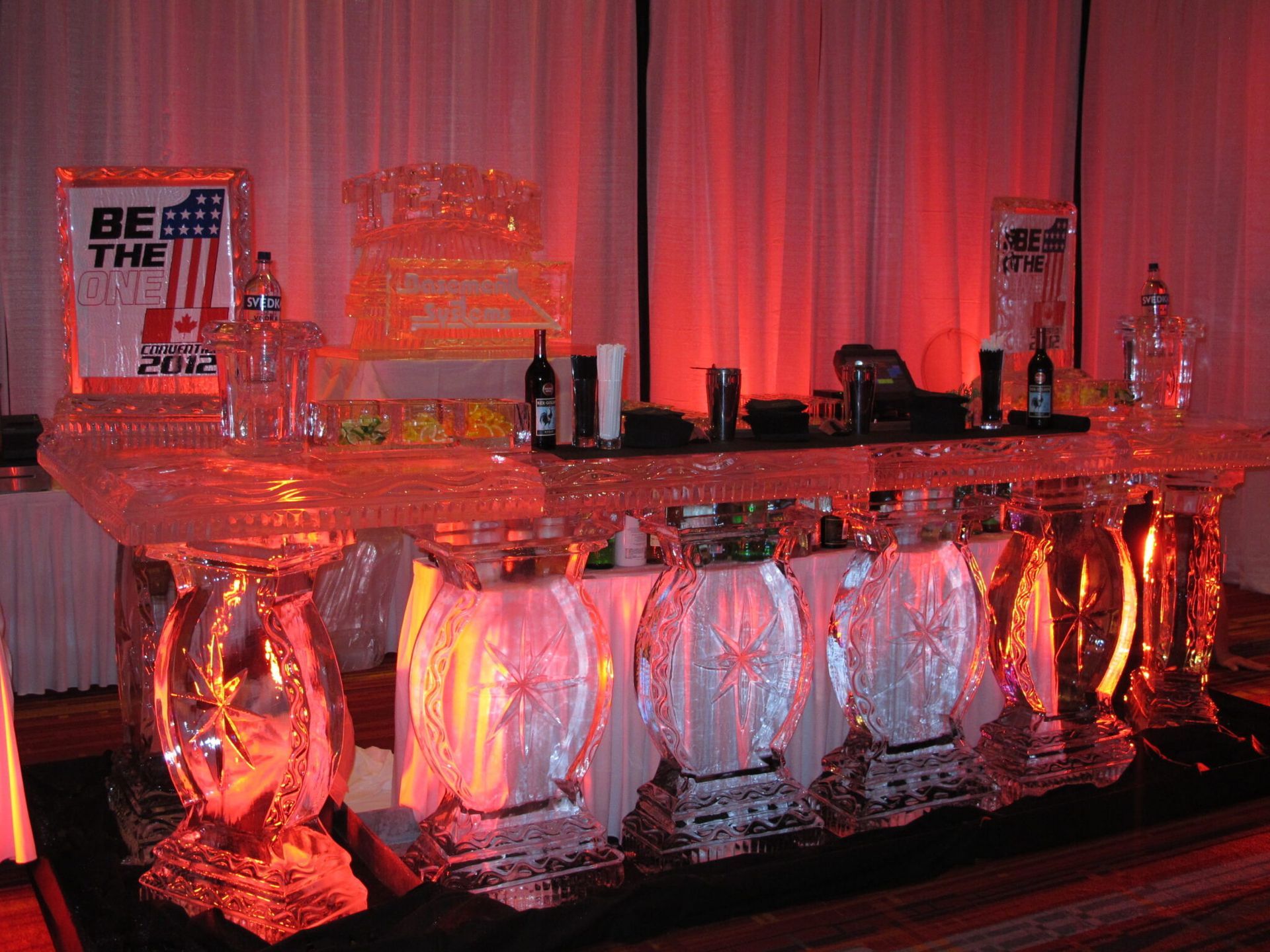 Red-lit bar with bottles and glassware on shelves and countertop