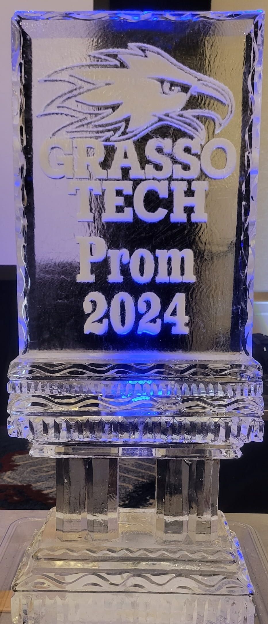 Glass trophy engraved “DASSO TECH Prom 2024” with a lion logo, lit with blue-purple reflections