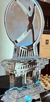 Clear glass trophy with a circular top on a pedestal, displayed on a table at an event