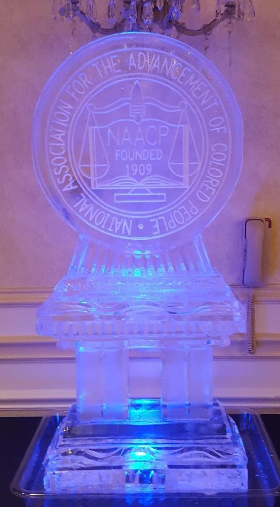 Clear acrylic award trophy glowing blue on a reflective base indoors