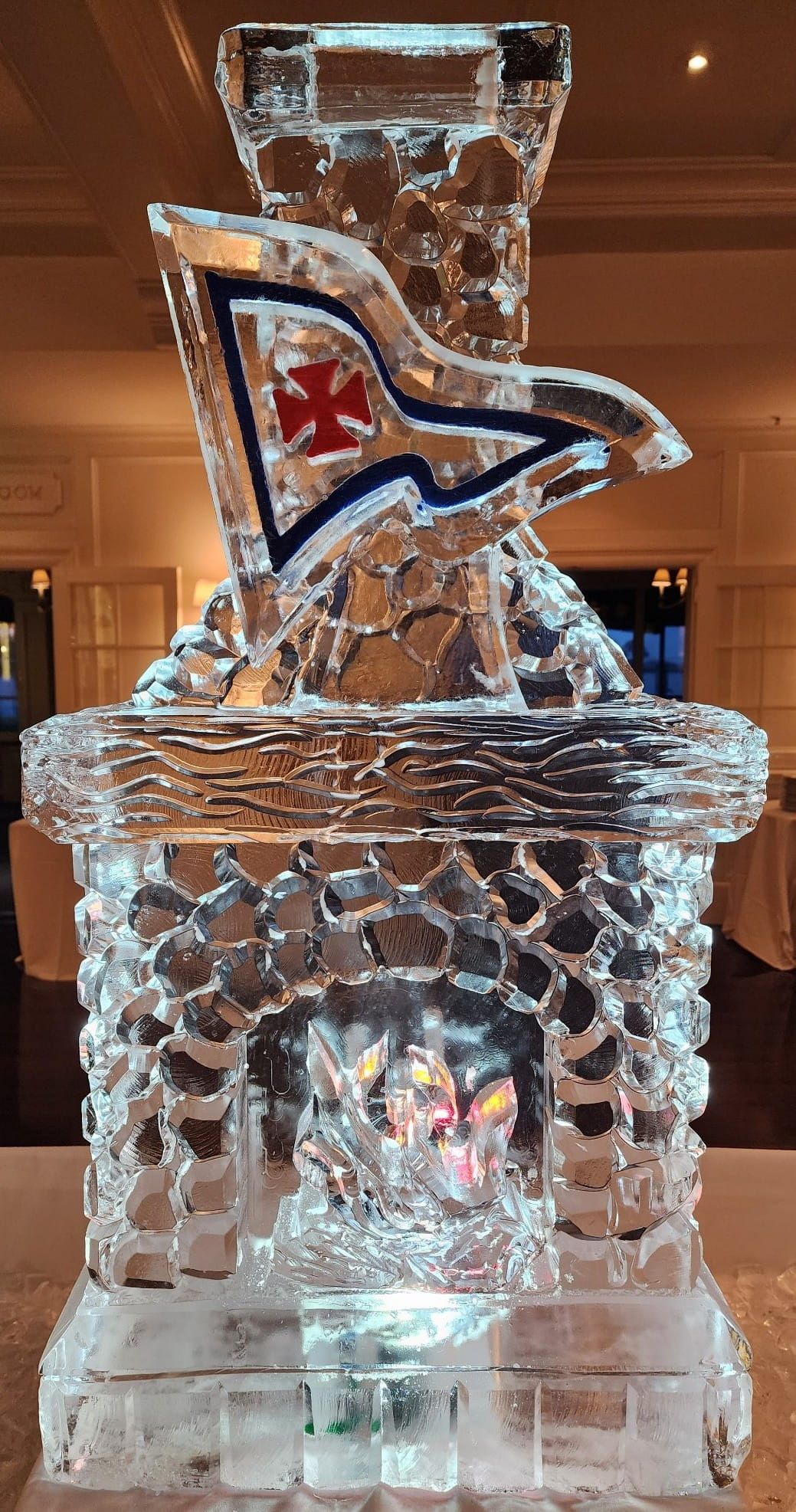 Ice sculpture of a treasure chest with a flag, lit from below in a dim indoor setting