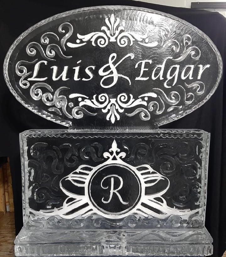 Decorative black sign with ornate white lettering reading “Luis & Edgar” and a monogrammed “R” below