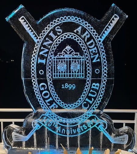 Blue ice sculpture of the Tinnis Arden Golf Club logo at night, with “1899” and “150th anniversary” text