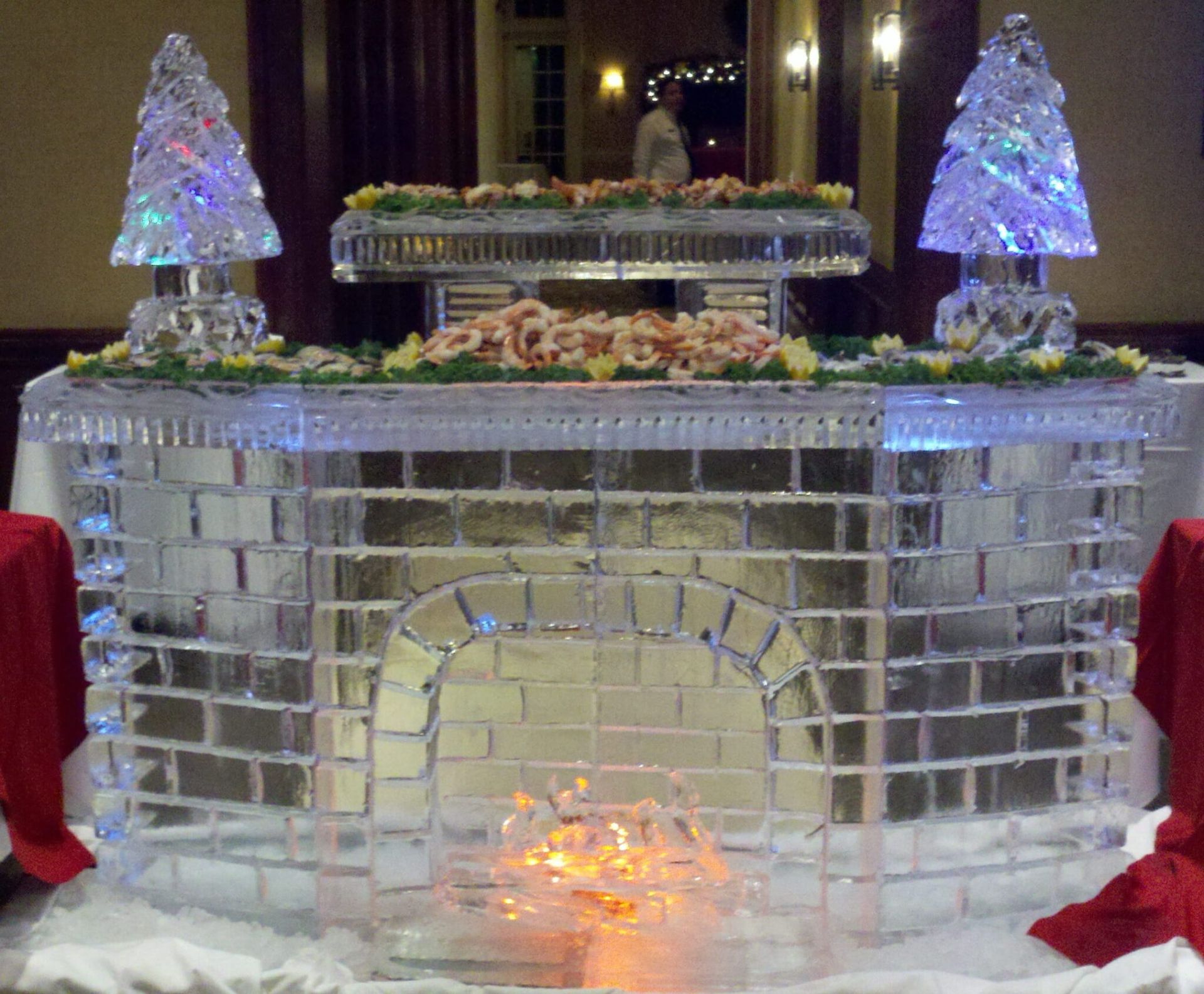 Ice sculpture dessert display with lit tree decorations on a banquet table