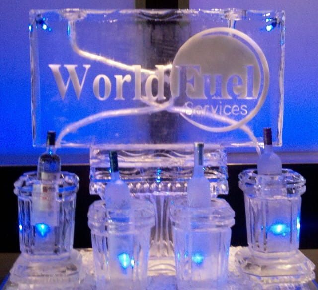 World Fuel Services logo on clear acrylic display with blue-lit devices on a reflective surface