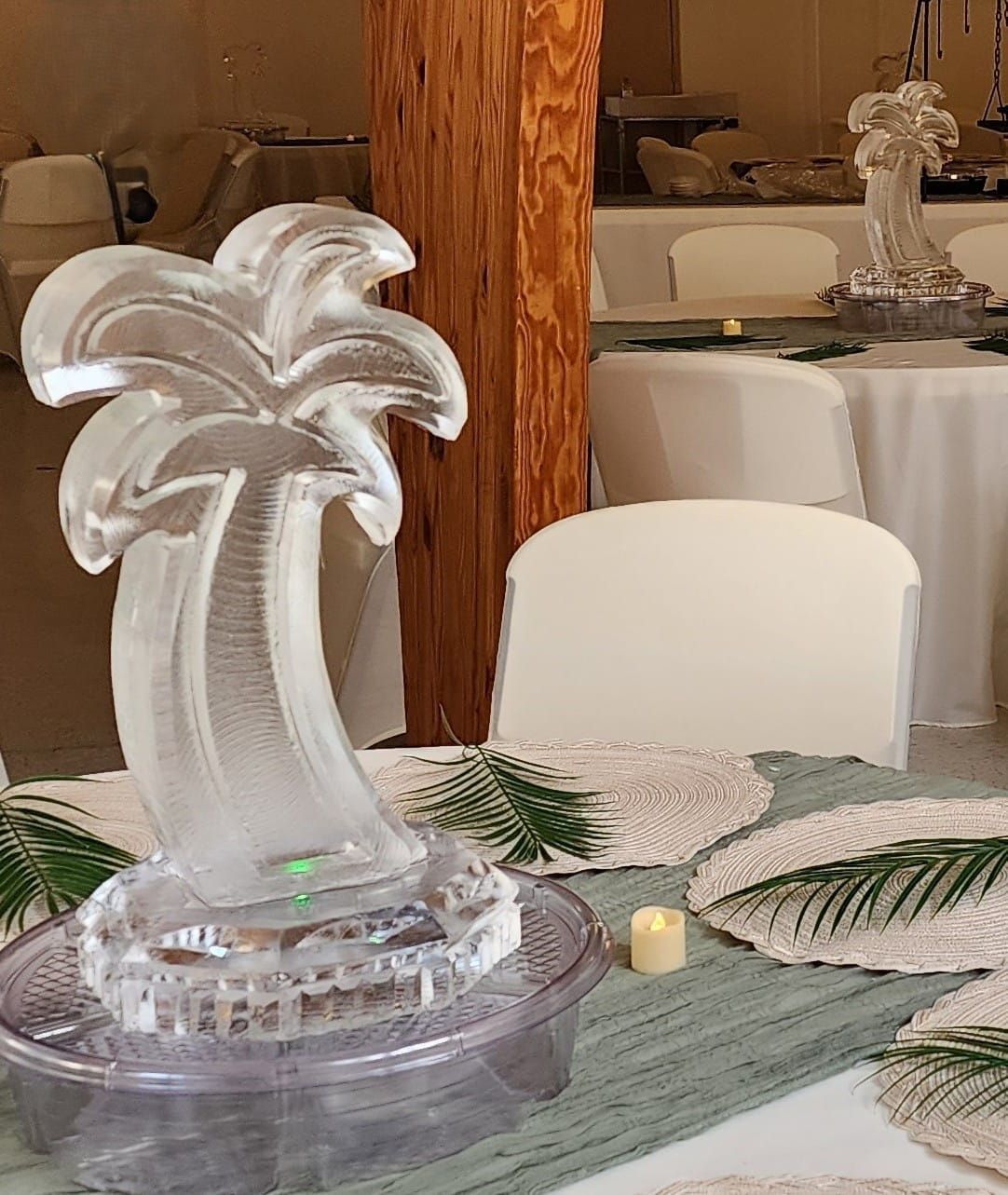 Clear palm tree sculpture centerpiece on a decorated dining table in a banquet room