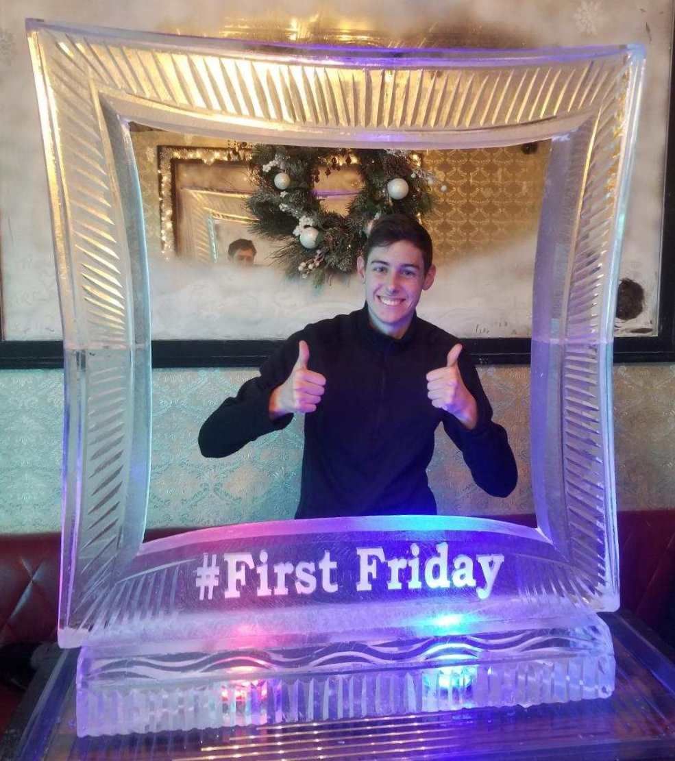 Person giving two thumbs up inside a lit frame with “#First Friday” at the bottom.