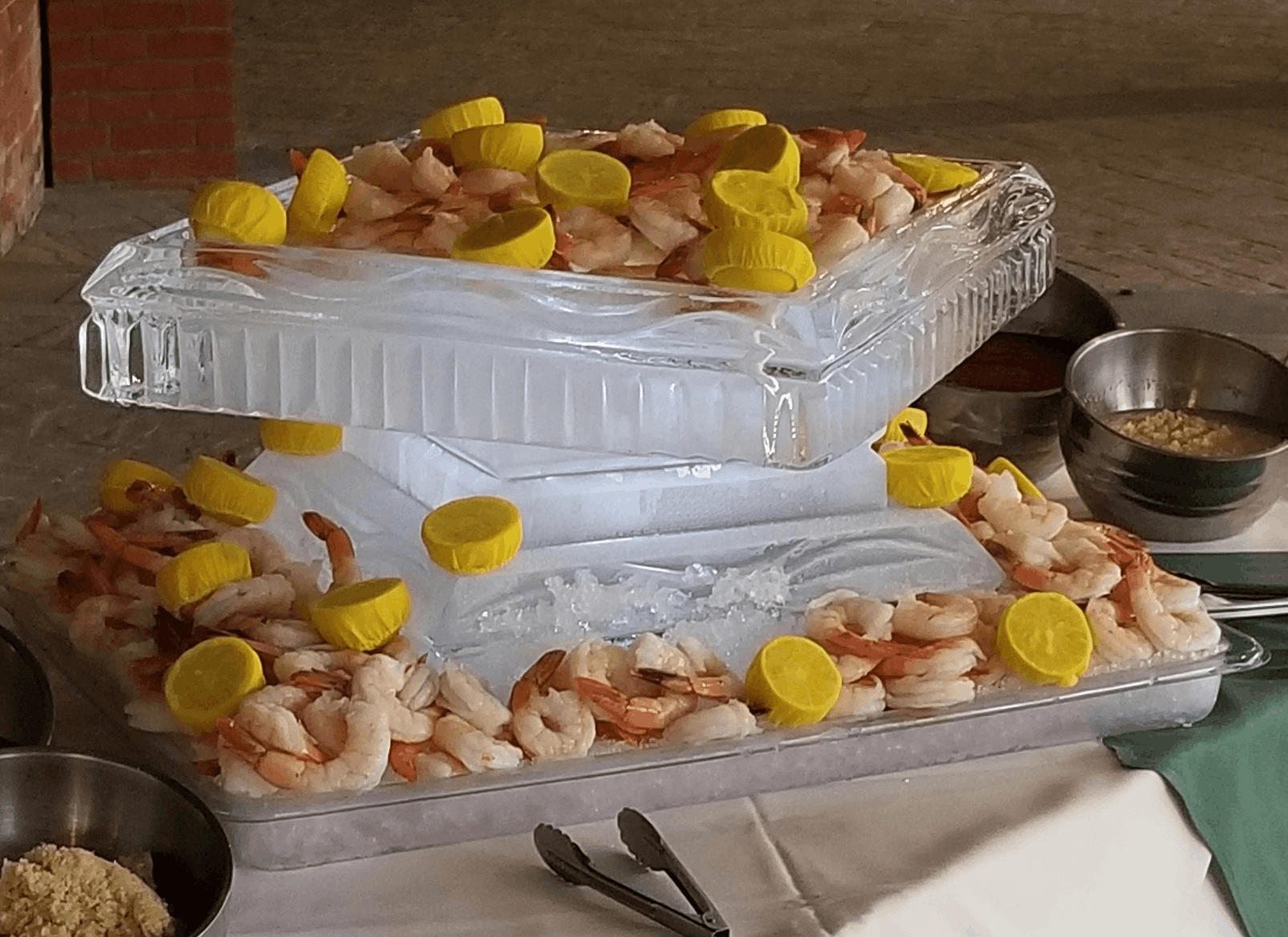 Two trays of assorted sweets with yellow garnish on a table, covered in clear plastic wrap.