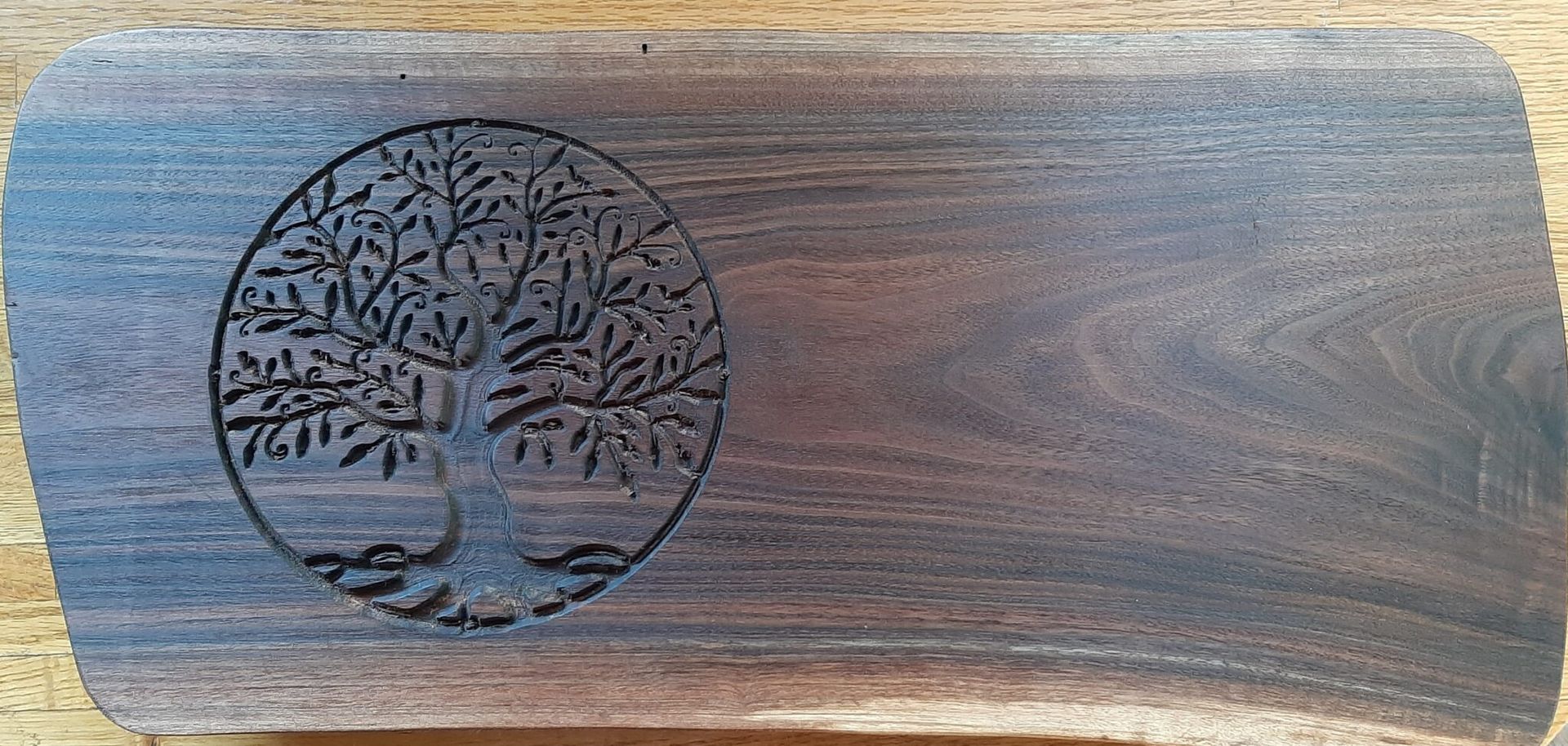 Wood-grain wooden plaque with a carved tree emblem on the left