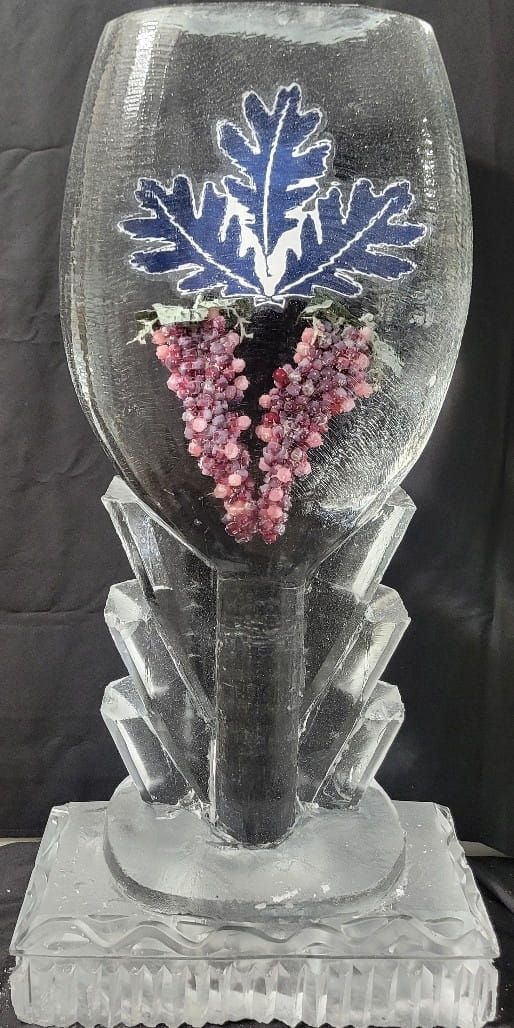 Clear glass vase with a blue flower and pink berries on a black stem, on a clear base