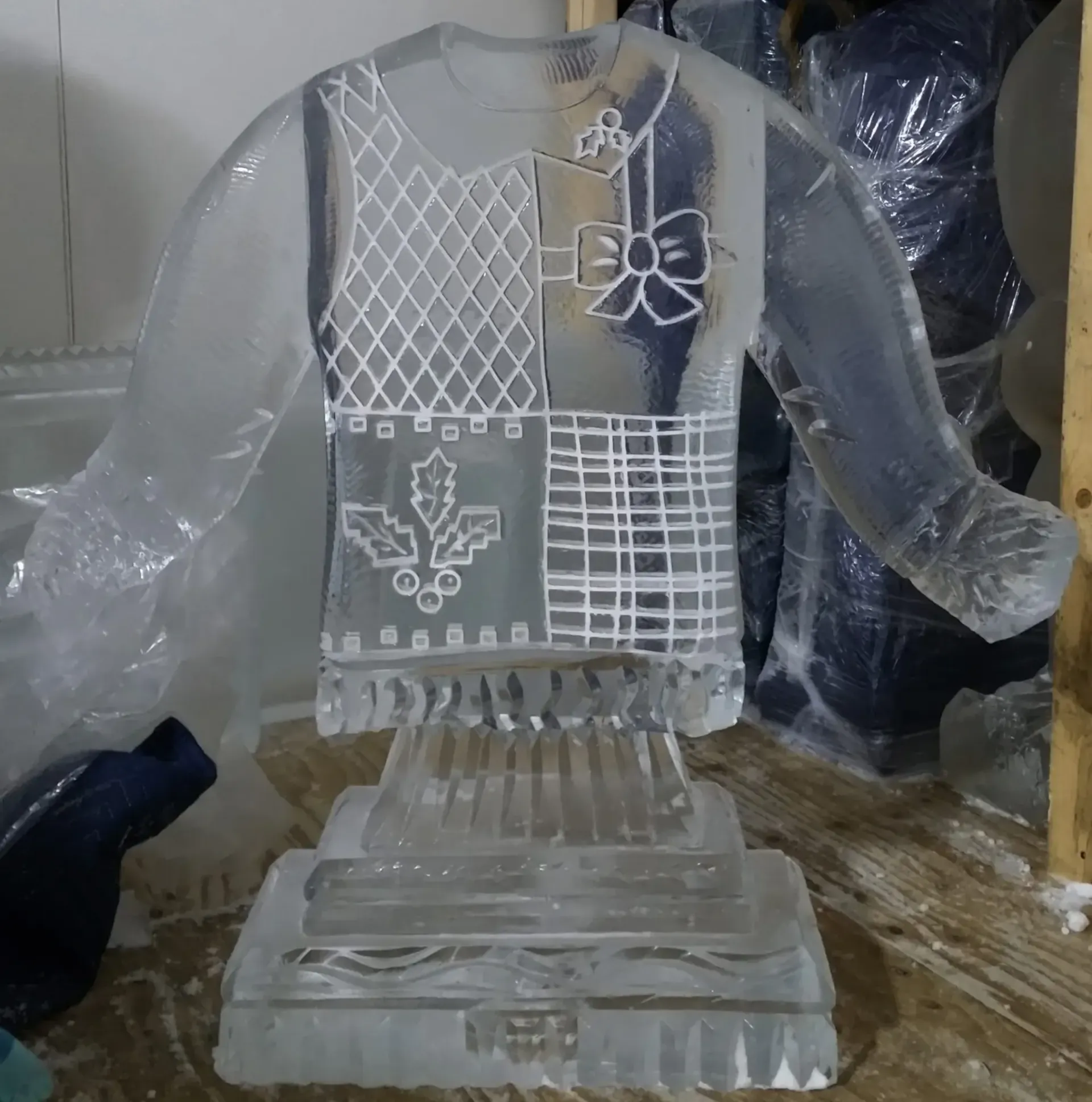 Clear glass angel figurine with etched design and wings on a pedestal, wrapped in protective plastic.