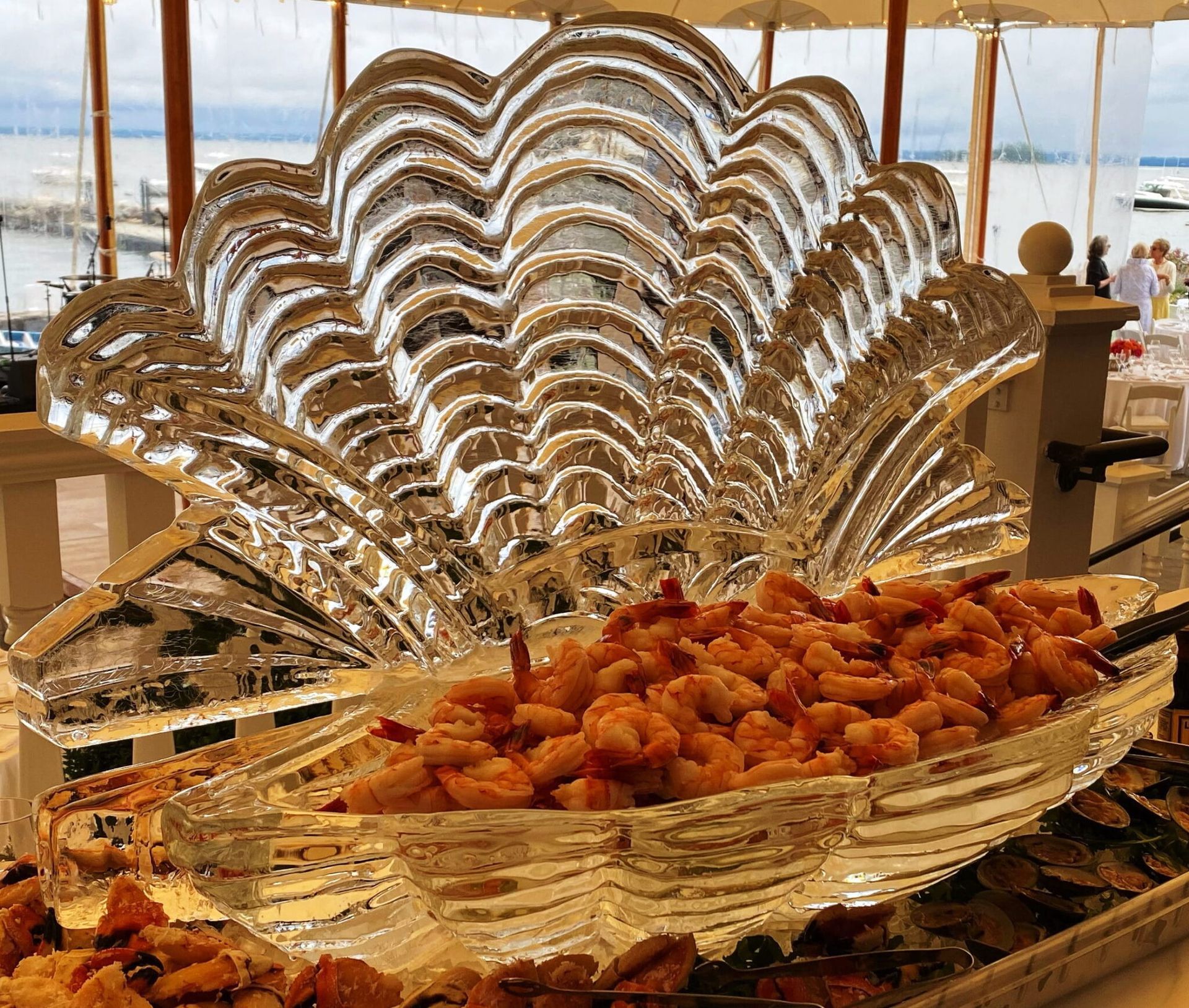 Ornate glass serving dish filled with pastries at a buffet table by the sea
