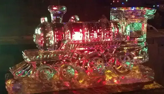 Colorful illuminated glass train sculpture glowing red, green, and clear in the dark