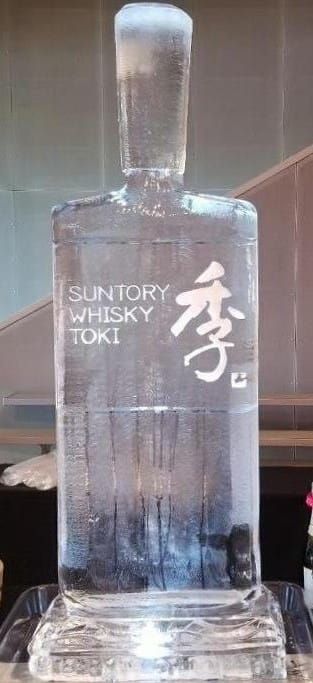Clear square bottle of Suntory whisky with frosted stopper and Japanese label on a table