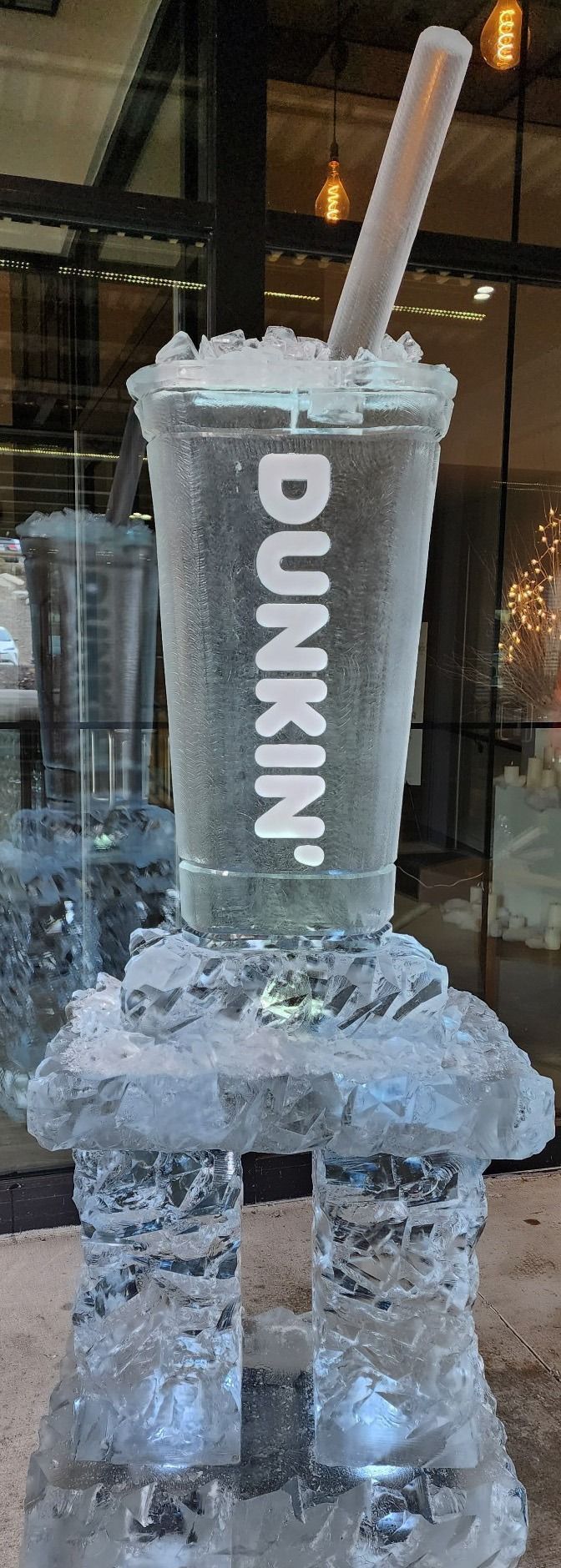 Dunkin’ iced drink in a clear cup with a straw, stacked inside an ice sculpture-like chair