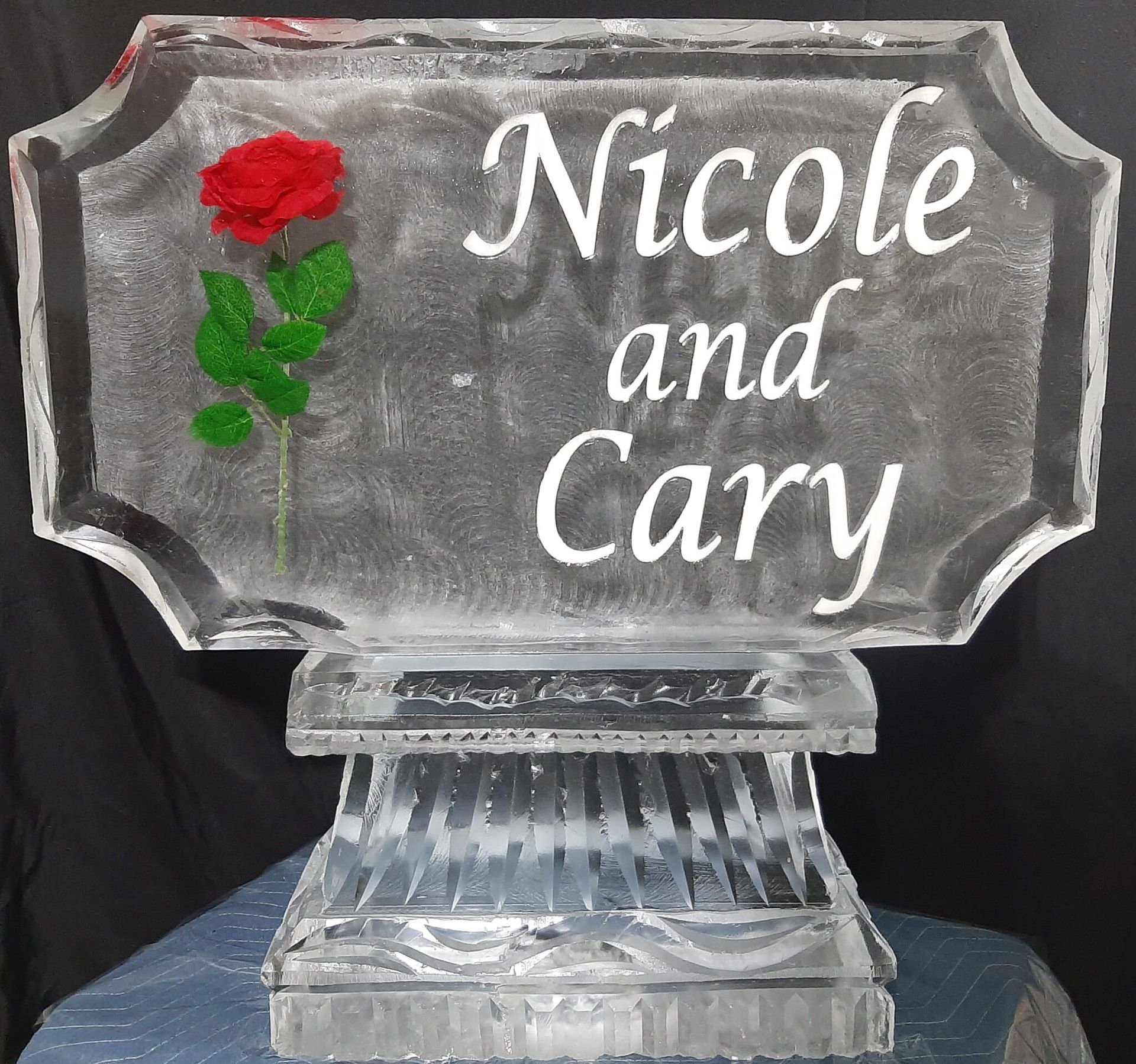 Custom engraved glass plaque reading “Nicole and Cary” with a red rose