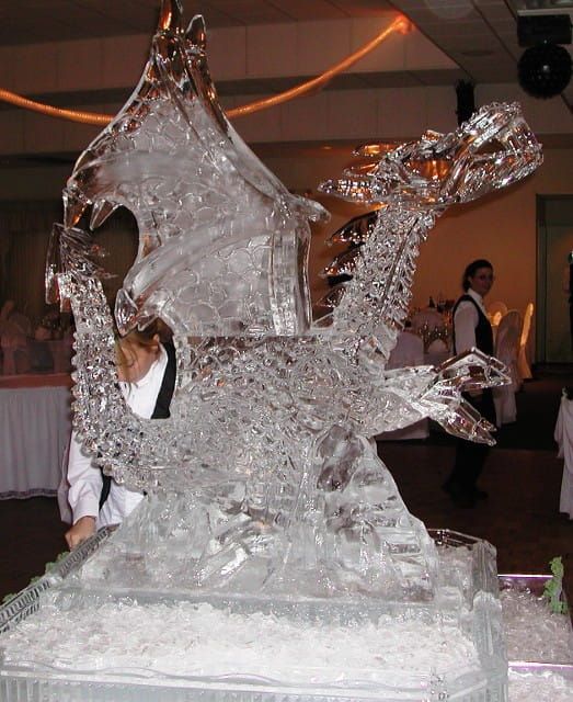 Crystal dragon sculpture at an indoor event, shown on a pedestal with people in the background