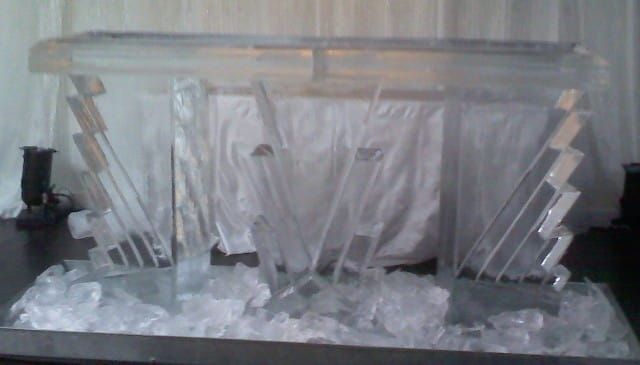 Clear crystal award or trophy on a base with faceted sides, displayed against a white backdrop.