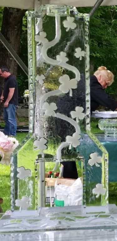 Vertical clear acrylic art panel with white floral patterns, displayed outdoors at an event