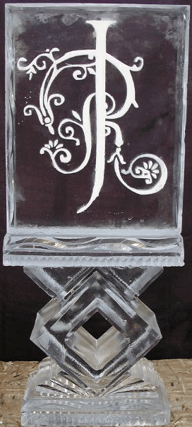 Monogrammed clear glass plaque with a decorative white letter design on a black background.