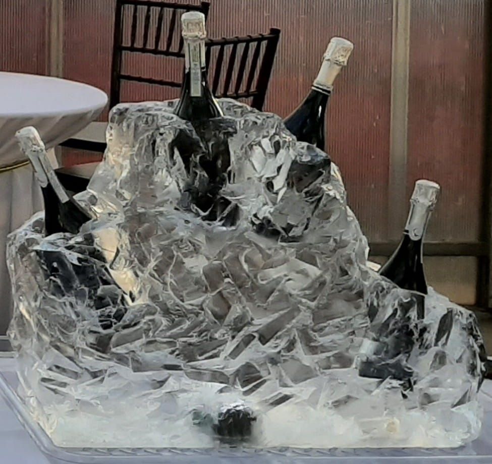 Four champagne bottles chilling in a clear ice sculpture on a table