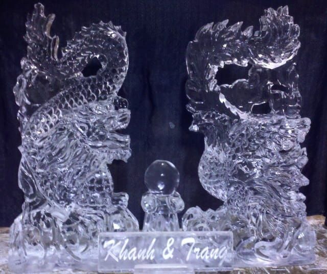 Clear crystal dragon sculptures flanking a small figure, with “Rohan & Fran” engraved below