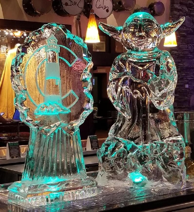 Two glowing ice sculptures on a bar, lit turquoise and standing on a reflective counter