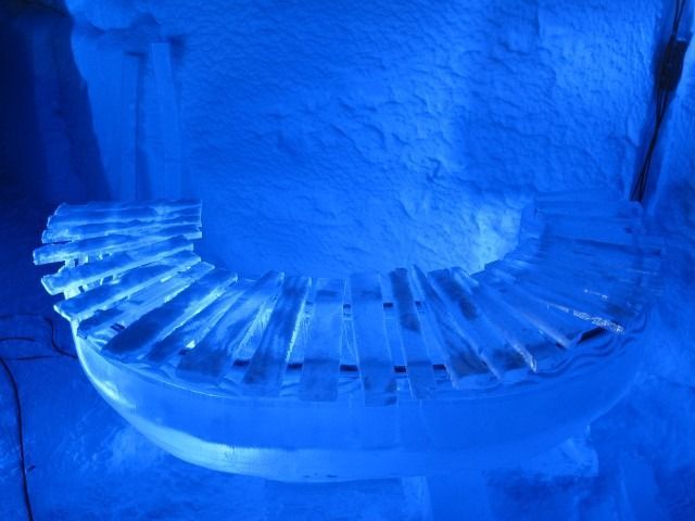 Blue-lit spiral staircase with curved steps and stone wall background