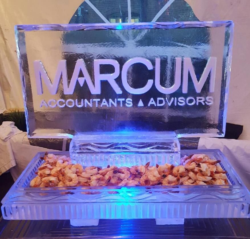MARCUM Accountants & Advisors logo on a lit ice sculpture above a tray of appetizers