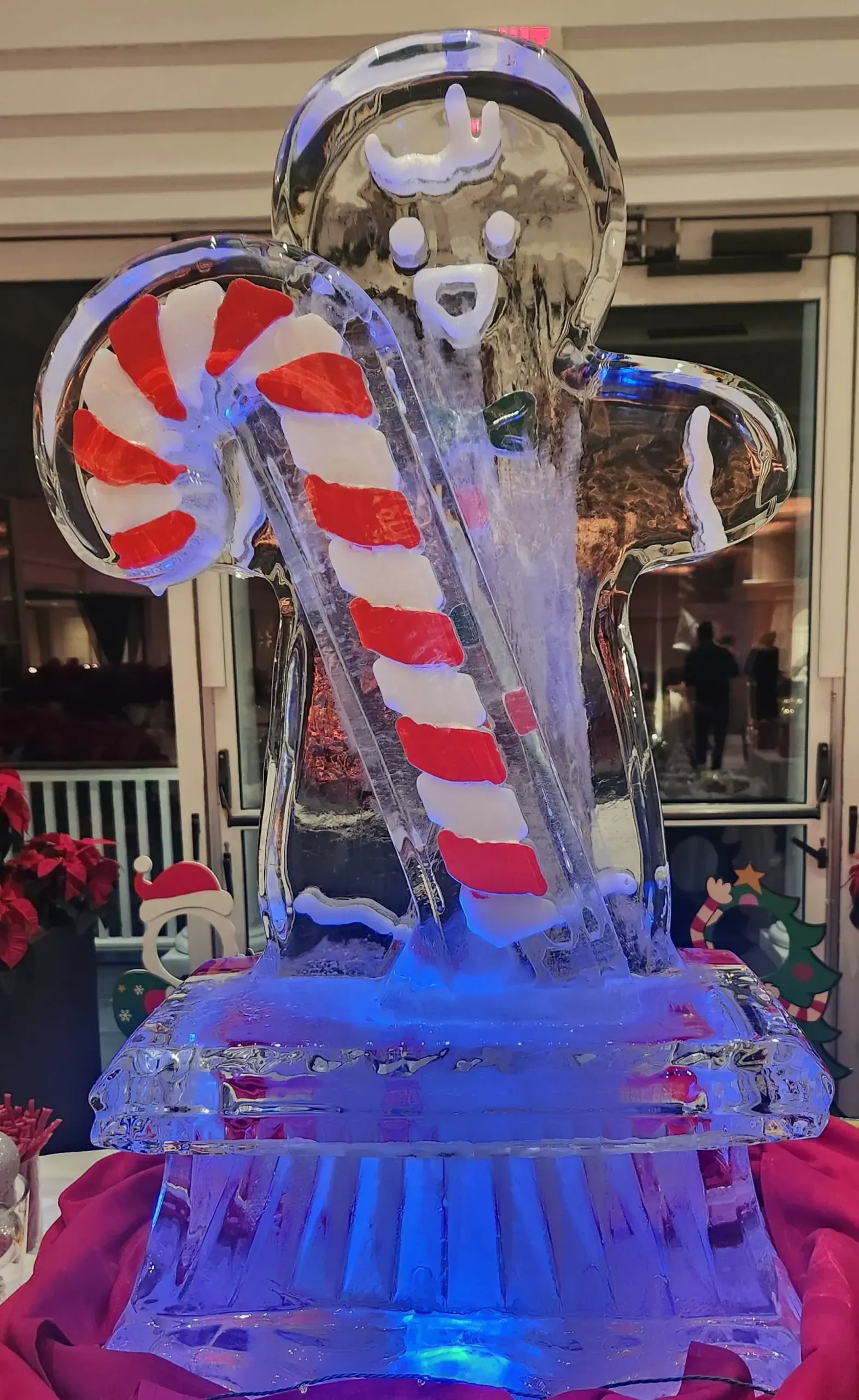 Candy cane and gingerbread holiday display with blue lights and a snowy base