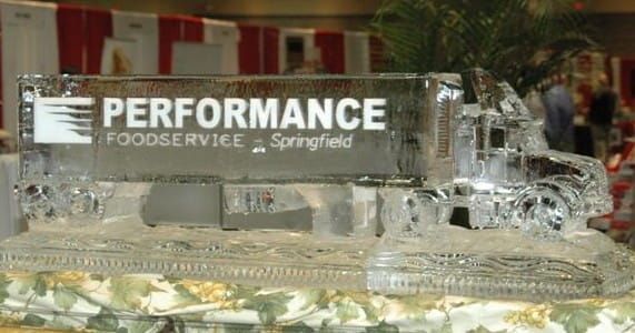 Ice sculpture with “PERFORMANCE Foodservice” logo at a banquet or trade show display.