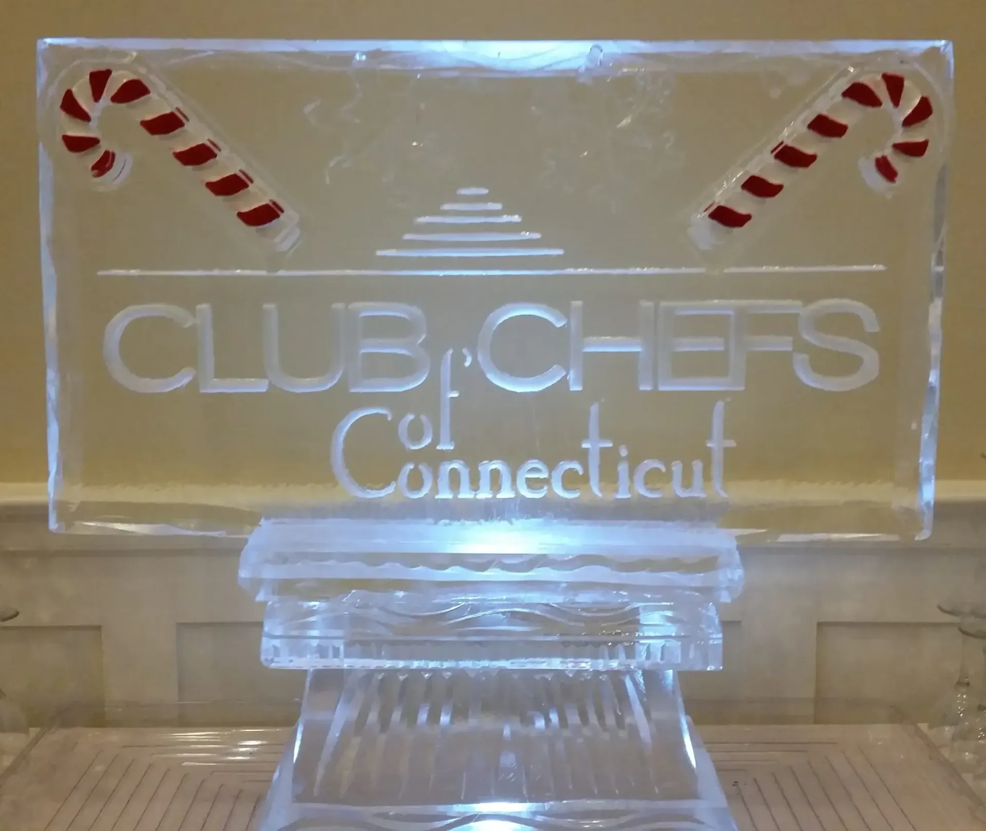 Illuminated Club of Chefs Connecticut ice sculpture with candy cane accents on a base