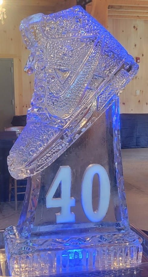 Blue-lit ice sculpture with the number 40 on a pedestal inside a wooden room.