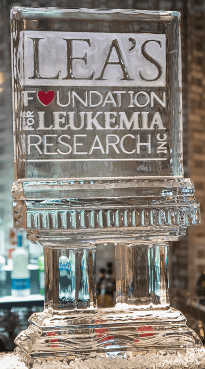Clear glass award engraved “LEA’S Foundation for Leukemia Research” on a reflective surface