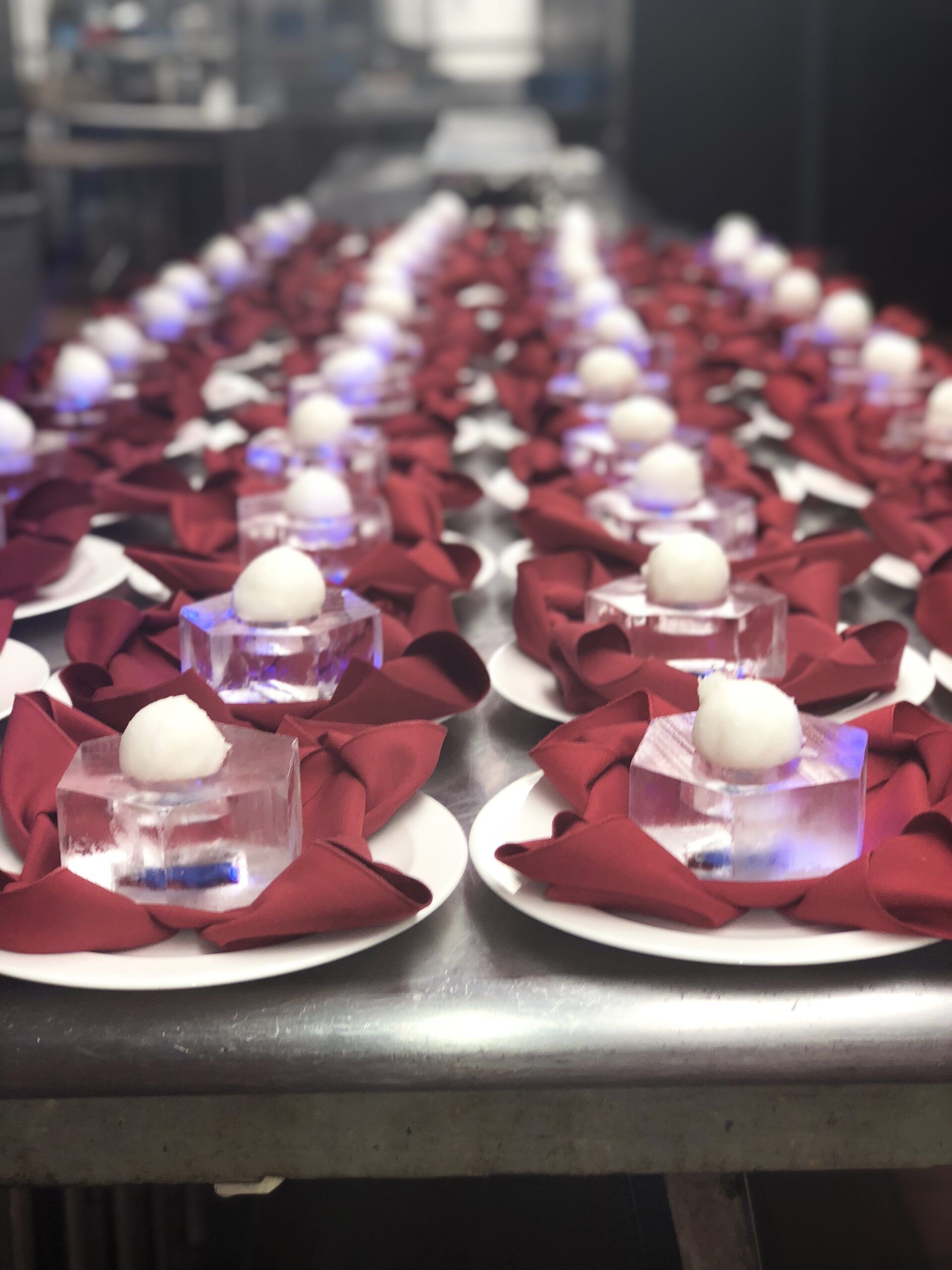 Rows of white desserts on red napkins and clear dishes, arranged on trays at a catering table.