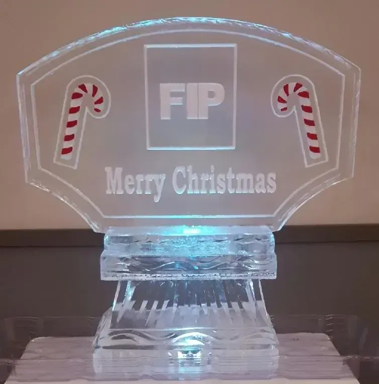 Clear acrylic Christmas trophy with candy canes and “FIP Merry Christmas” text, lit with blue light