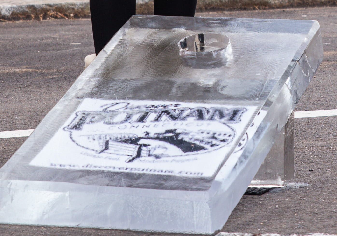 Ice sculpture of a building logo on pavement, with a small flame or candle on top.