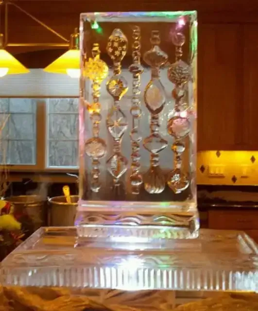 Clear glass decorative sculpture with etched oval patterns, lit by colorful lights in a kitchen.